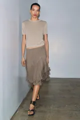 Falda corta de tiro medio con cintura elástica, confeccionada en tejido de viscosa. Presenta un diseño asimétrico con volantes en el bajo.