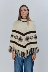 Poncho tejido de lana en color crudo con detalles geométricos en marrón oscuro y flecos en el ruedo.