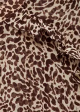 Vestido corto de manga larga con cuello redondo, confeccionado en tejido fluido con estampado animal print de leopardo. Presenta detalles drapeados, diseño entallado y cierre de botón en la parte posterior.