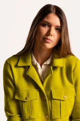 Chaqueta color verde lima de tejido en lana, con cuello clásico, cierre frontal con botones dorados y cuatro bolsillos con solapa en el frente.