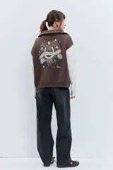 Cardigan de punto con diseño bicolor, cuerpo en color marrón y mangas largas en color crema con textura trenzada. Presenta cuello polo, cierre frontal con cremallera y puños acanalados.