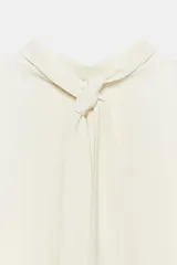 Vestido midi fluido de cuello alto y manga corta tipo capa. Presenta un diseño minimalista con bajo recto y aberturas laterales, con cierre en la espalda.