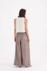 Pantalon tipo palazzo de corte amplio y tiro alto, confeccionado en tela con textura labrada. Presenta pinzas en la cintura y bolsillos laterales.