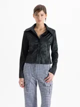 Camisa de jacquard con diseño de flores sutiles, color blanco, con cuello amplio de puntas marcadas, mangas largas con puños y cierre frontal con botones.