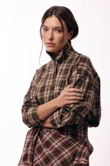 Camisa de corte recto y mangas largas con estampado de cuadros tartán en tonos marrones y beige. Presenta cuello camisero y cierre frontal con botones.