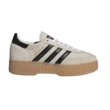 Championes Adidas modelo Handball Spezial Bold, con capellada de gamuza en tono beige, icónicas tres tiras laterales en cuero negro y refuerzo en el talón a tono. Presentan una llamativa suela de plataforma de goma color caramelo con diseño texturizado.