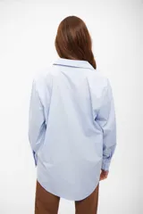Camisa de corte oversize con cuello clásico, cierre frontal de botones y mangas largas con puños abotonados.