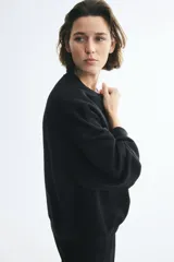 Buzo oversized negro con interior cepillado suave, cuello redondo con ribete acanalado, hombros caídos y puños y bajo con ribete acanalado.
