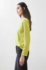 Remera de manga larga color verde lima, con escote redondo y detalle de bordados calados en forma de pico en la zona del pecho.