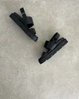 Sandalia negra de plataforma gruesa, con dos tiras anchas sobre el empeine y tira ajustable en el talón.