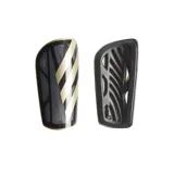 Espinilleras Adidas Tiro League negras con detalles dorados. Cuentan con placa protectora flexible, medias de compresión y refuerzo interior de EVA moldeada.