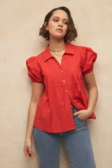 Camisa roja con cuello clásico, mangas cortas abullonadas y cierre frontal con botones.