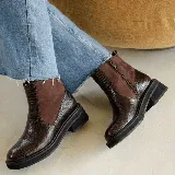 Bota corta de estilo chelsea con paneles laterales elásticos en contraste. Presenta una textura grabada tipo reptil en el cuero y una suela de plataforma dentada de goma negra.
