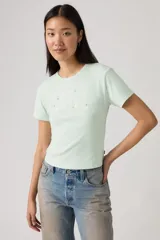 Remera de algodón color verde menta, con cuello redondo y mangas cortas. Presenta el logo de la marca estampado en el frente con detalles de pequeñas flores bordadas.