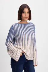 Sweater de punto con diseño de rayas verticales en dos colores, azul y crudo. Presenta cuello bote, mangas largas con terminación acampanada y un aplique decorativo en el pecho.