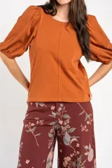 Remera de algodón negro con mangas cortas abullonadas, cuello redondo y costura central frontal.