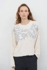 Buzo de tejido de punto color beige, con cuello redondo, mangas largas y detalle de bordado floral en color gris en la parte superior delantera.