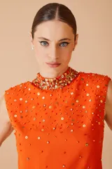 Blusa naranja sin mangas con cuello alto y apliques de lentejuelas y cuentas en el cuello y el cuerpo.