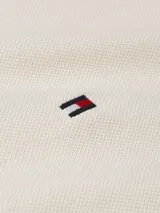 Chomba color crema de Tommy Hilfiger, corte slim, con cuello clásico, tapeta de dos botones y logo bordado en el pecho.