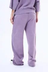 Pantalon de felpa color violeta con efecto lavado, de corte holgado y tiro medio. Cuenta con cintura elástica con cordón de ajuste y costuras laterales decorativas.