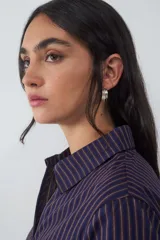 Camisa de manga larga confeccionada en popelina de algodón, con diseño de rayas verticales finas en tonos azul oscuro y naranja. Presenta cuello clásico, cierre frontal con cremallera y un corte ajustado al cuerpo.