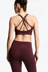 Top deportivo color bordó, de tejido funcional con sujeción media. Diseño con escote redondo, breteles dobles finos cruzados en la espalda y elástico cepillado en el bajo. Incluye copas forradas con relleno extraíble.