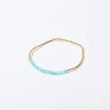 Pulsera elástica con cuentas doradas y cuentas facetadas color aguamarina.