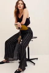 Pantalón fluido de tiro medio con diseño de rayas verticales metalizadas en tono dorado sobre base negra, corte amplio y silueta recta.