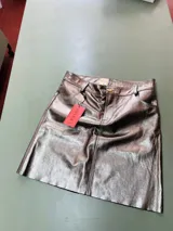 Falda midi de cuero sintético color bronce, corte recto y tiro alto.