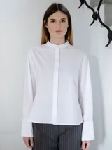 Camisa de corte recto y tejido semitransparente, con cuello mao y cierre frontal oculto por tapeta. Presenta mangas largas con puños anchos y un diseño minimalista.