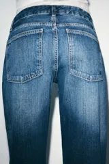 Jeans de tiro bajo y cinco bolsillos, de pierna ancha y larga. Cuenta con cierre frontal con cremallera y botón metálico.