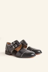 Zapato tipo oxford abierto en los laterales, confeccionado en cuero vacuno negro. Presenta doble tira con hebillas metálicas en el empeine y detalle de tachas plateadas en el contorno del talón y la puntera.
