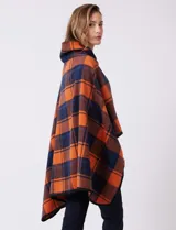 Capa de tejido cuadrille con diseño de cuadros en tonos marrón, beige y naranja. Presenta un cierre frontal con botón tipo trenca y bordes con ribete negro.