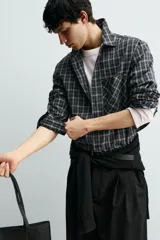 Camisa de corte relajado confeccionada en voile de algodón, con estampado de cuadros. Presenta cuello solapa, manga larga con puños abotonados, bolsillo de parche en el pecho y cierre frontal de botones.