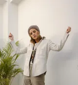 Campera de cuero color beige claro, estilo sobrecamisa o chaqueta ligera, con cuello camisero, cierre frontal con broches de nácar y dos bolsillos de parche en el pecho.