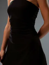 Vestido corto negro strapless, de corte ajustado en el torso con fruncidos laterales y falda levemente evasé.