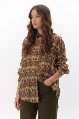 Camisa de manga larga con estampado de tapiz en tonos marrones, verdes y beige. Tiene cuello clásico y cierre frontal con botones.