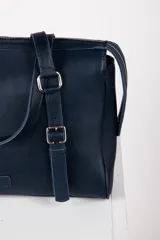 Cartera tipo bolso de mano y hombro de cuero color bordó, con diseño estructurado, doble asa corta y detalles de correas con hebillas metálicas en el frente.
