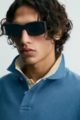 Polo de algodón con estructura piqué, color azul deslavado. Presenta un corte regular fit, cuello solapa con cierre de botones, manga corta con acabado en rib y bajo asimétrico con aberturas laterales.