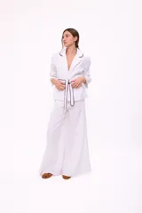 Pantalón de tiro alto, pierna ancha y largo, color beige claro con finas rayas verticales en tono oscuro. Presenta un diseño de cinco bolsillos estilo jean.