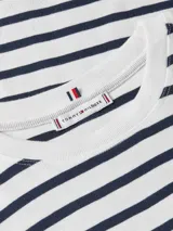 Remera de algodón con rayas horizontales azul marino y blancas, cuello redondo y mangas cortas con detalle enrollable y botón dorado. Presenta un pequeño logo bordado en el pecho.