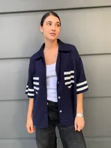 Camisa azul marino de manga corta con rayas horizontales blancas en mangas y bolsillo.