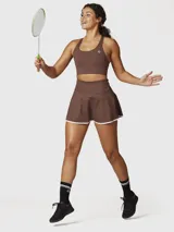 Top deportivo color chocolate con espalda cruzada y logo blanco en el frente. Ofrece sujeción media y está confeccionado con tecnología Aloe Vera para mayor suavidad.