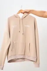 Canguro color beige con capucha, bolsillo tipo canguro y puños y cintura acanalados. Estampado frontal con el logo de la marca Brokers Wear y la frase "Good Time Makers".