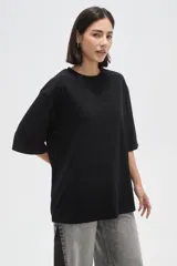 Remera de corte holgado, color negro, con cuello redondo y mangas cortas.