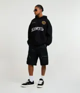 Bermuda baggy de poliéster y algodón color negro, con doble trabilla en la cintura, bolsillos cargo laterales con cremallera y diseño holgado.