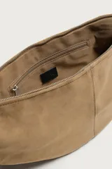 Bolso de hombro de gamuza marrón con diseño curvado, compartimento principal con cierre de cremallera y asa larga de cuero negro.