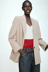 Blazer de corte recto y diseño estructurado en color beige, con cuello solapa, manga larga y cierre frontal con un solo botón. Cuenta con bolsillos delanteros con solapa y forro interior en color negro.