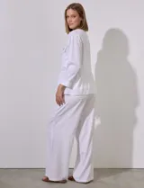 Chaqueta blanca de tencel con cuello con solapa, escote en V y abertura central con broches internos. Tiene corte en la cintura y bolsillos delanteros.