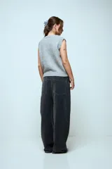 Chaleco de punto gris de corte holgado y largo cropped, con cuello redondo y sisas acanaladas. Presenta detalles bordados decorativos en la parte superior del pecho en tonos rojo y azul.